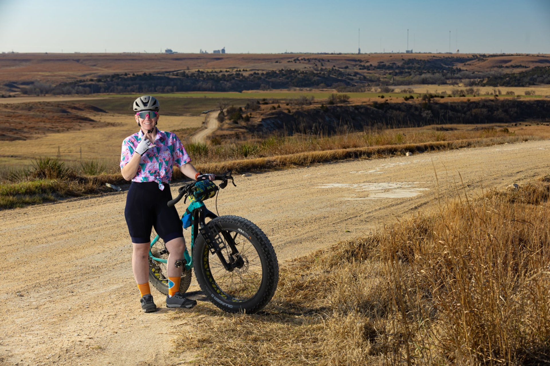 Amanda Duling, founder of More Than Miles, standing with her fat bike on a gravel road in the open prairie